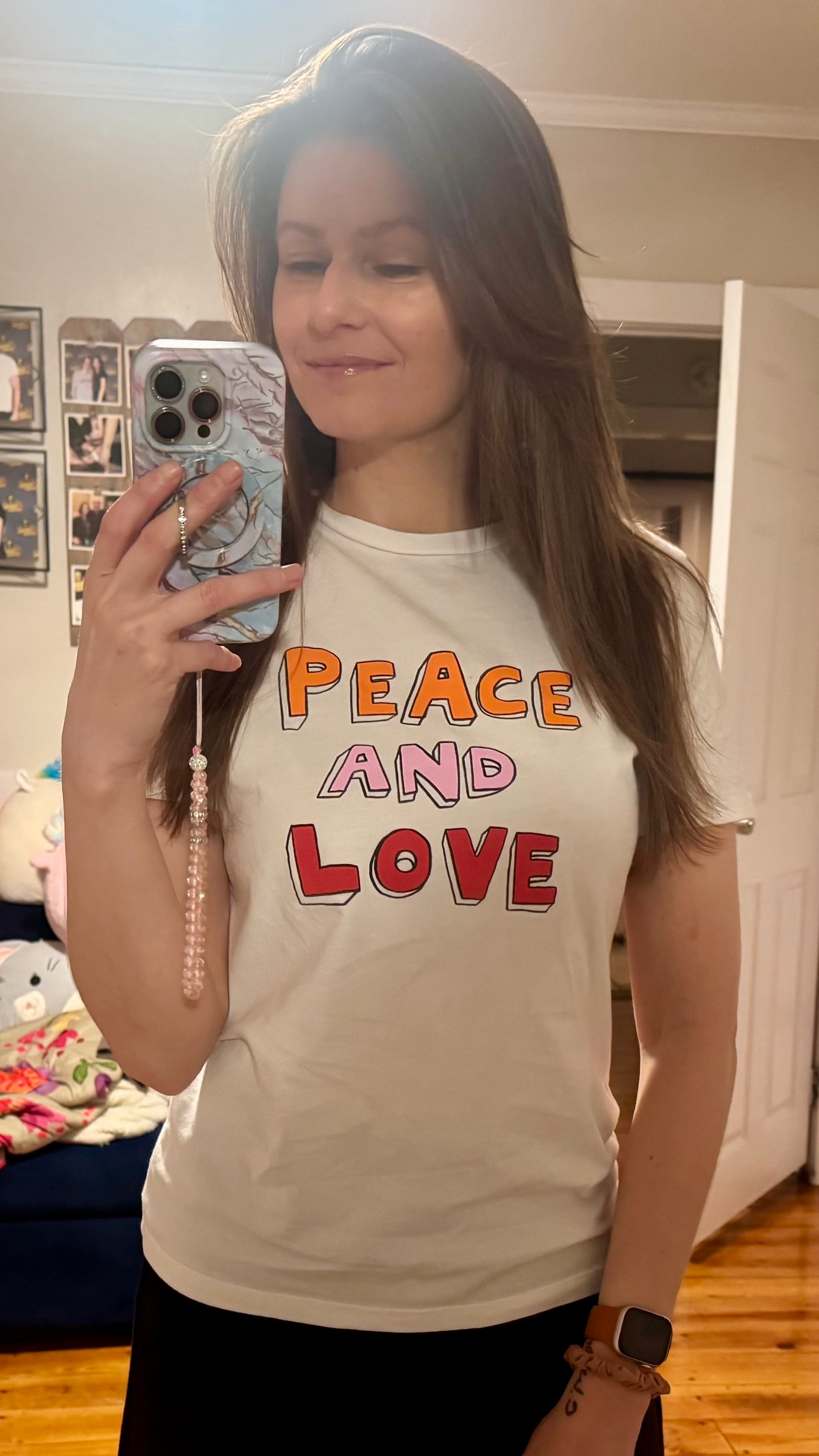 A mirror selfie of Sarah wearing a t-shirt that says "Peace and Love"